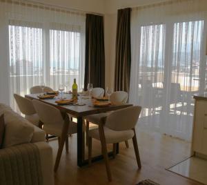 a dining room table with white chairs and a table and a couch at The Olive Trees Penthouse - two bedroom in Bar