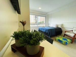 a living room with two potted plants and a bed at Studio Connect PUC in Porto Alegre
