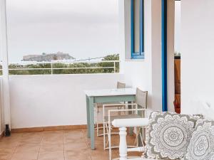 a table and chairs on a balcony with a window at Lindos Athena in Lindos