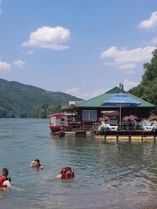 un grupo de personas nadando en un lago con una casa en Drinska čarolija Višegrad, en Višegrad