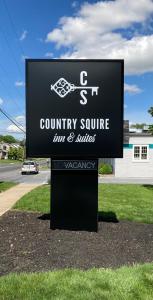 a sign for a county square inn and suites at Country Squire Inn and Suites in New Holland