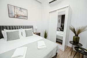 a white bedroom with a large bed and a mirror at M & N Guesthouse in Volos
