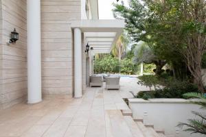 an outdoor patio with white columns and trees at Luxurious & Exclusive Villa, 10 min from the beach in Herzelia 