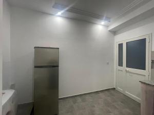 a refrigerator in a white room with a window at Deluxe apartment in Kelibia