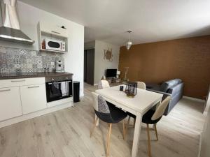 una cucina e un soggiorno con tavolo e sedie bianchi di T2 refait à neuf sur le thème oriental a Rodez