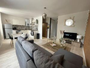 a living room with a gray couch and a kitchen at T2 refait à neuf sur le thème oriental in Rodez