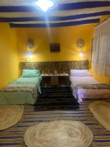 Habitación con 2 camas y pared azul y amarilla. en Dar Garindi, en Asilah