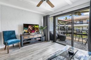 a living room with a tv and a blue chair at Casa de Emdeko 221 in Kailua-Kona