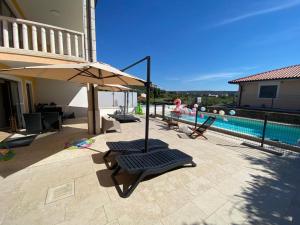 塞科夫列POP'S POOL PLACE的一个带两把椅子和一把遮阳伞的庭院,毗邻一个游泳池