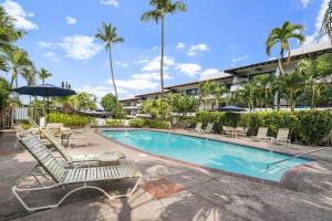 a swimming pool with lounge chairs and an umbrella at Casa de Emdeko 221 in Kailua-Kona