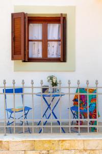 un tavolo e sedie su un balcone con finestra di Bluebell House Halki a Calchi (Halki)