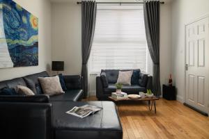 a living room with a black leather couch and a table at Nythfa in Llanrwst