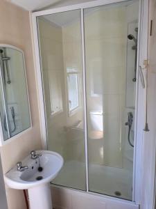 a bathroom with a glass shower and a sink at Serenity in Monreith