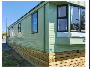 a green building with windows on the side of it at Serenity in Monreith