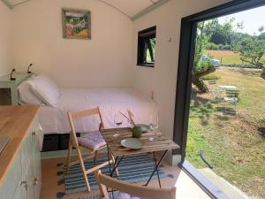 a room with a table and a bed and a window at Apple Orchard Shepherd Huts in Staple Cross