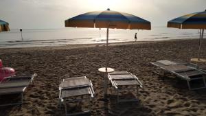 una playa con sillas, mesas y sombrilla en Hotel Sirena en Pineto