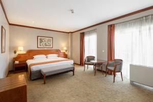 テッサロニキにあるホリデー イン テッサロニーキのベッド、テーブル、椅子が備わるホテルルームです。