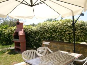a table and chairs with an umbrella and a grill at La Loggina Maxi in Tuoro sul Trasimeno