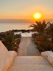 eine Treppe, die zu einem Sonnenuntergang über dem Meer führt in der Unterkunft Deadsea OCTAGON in Madaba