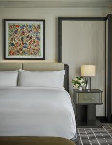 a bedroom with a white bed and a table with a lamp at Pendry Newport Beach in Newport Beach