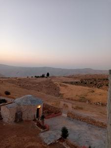 una vista del desierto con un edificio en el primer plano en Dana Nabil Ecu Camp House - Main Gate Dana nature reserve en Dana