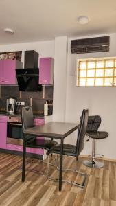 een keuken met een zwarte tafel en stoelen en roze kasten bij Bungalow Alex in Dresden