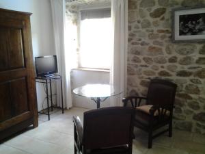 a living room with a table and chairs and a television at Le Mas de la Musardiere chambres d hotes in Les Assions