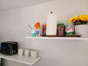a shelf with coffee cups and a toaster and flowers at Departamento XIBI in San Salvador de Jujuy