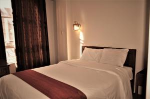 a bedroom with a large bed with white sheets and a window at CESAR'S HOTEL PERU in Puno