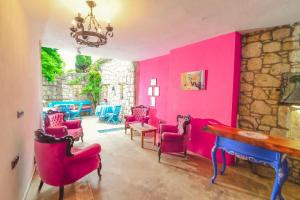 um quarto com paredes cor-de-rosa, cadeiras vermelhas e uma mesa em Bedirhan Konak Otel em Alacati