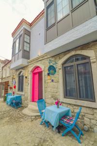 une table et des chaises à l'extérieur d'un bâtiment avec une porte rouge dans l'établissement Bedirhan Konak Otel, à Alaçatı