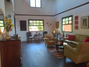 a living room with couches and chairs and windows at Guapimirim Casa de Campo in Guapimirim