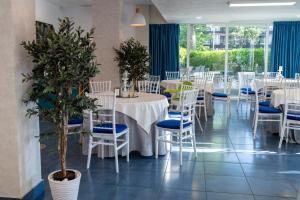 a restaurant with white tables and chairs and plants at Hotel Apollo in Mamaia +123 photos