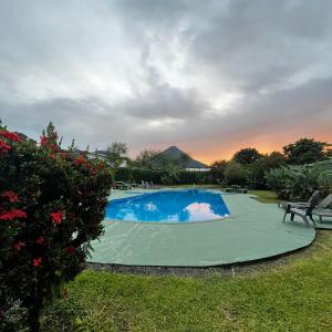 a swimming pool in a yard with a sunset in the background at Hotel Villa Fortuna, Volcan Arenal, Costa Rica. in Fortuna