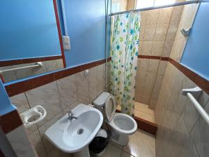 y baño con aseo, lavabo y ducha. en Hostal EL TAMBO en Ica