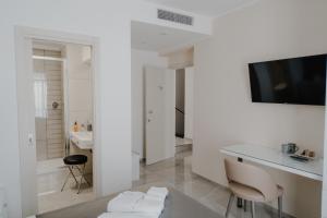Habitación blanca con escritorio y TV en la pared. en RIMIR Hotel & Centro Benessere, en Montecilfone