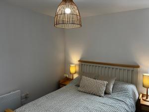 a bedroom with a bed and a pendant light at The Salt Locker in Porthleven