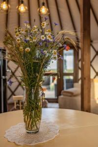 wazon wypełniony kwiatami na stole w obiekcie Jurtowe Wzgórze Glamping w mieście Grabinek