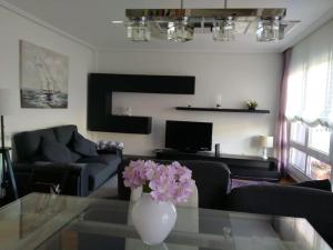 uma sala de estar com um vaso de flores numa mesa de vidro em Apartamento Lekeitio, Garaje y WIFI em Lekeitio