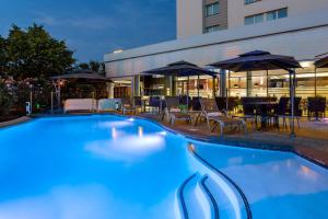 einem Pool mit Stühlen und Sonnenschirmen vor einem Gebäude in der Unterkunft Courtyard by Marriott Toulouse Airport in Toulouse