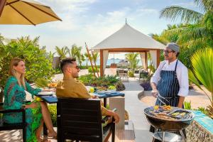 een groep mensen aan een tafel met eten bij The Ritz-Carlton Ras Al Khaimah, Al Hamra Beach in Ras al Khaimah