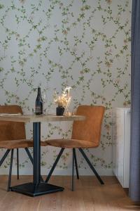 a dining room table with chairs and a wall with floral wallpaper at B&B T'Rest - Park ter Rijst in Heikruis