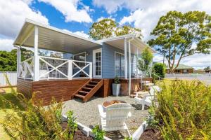 una pequeña casa azul con porche y 2 sillas blancas en Hamptons House on Hunter with fire pit, en Aberdare