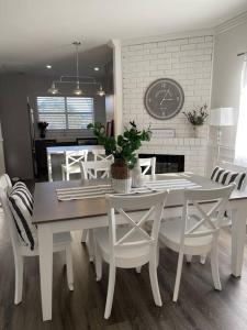 a dining room with a table and chairs and a clock at Hamptons House on Hunter with fire pit in Aberdare