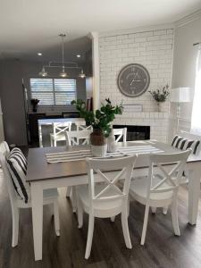 AberdareにあるHamptons House on Hunter with fire pitのテーブルと椅子と時計のあるダイニングルーム