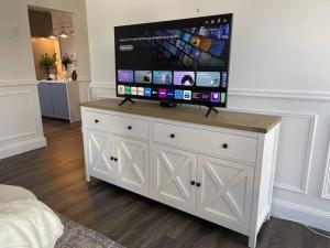 a flat screen tv on top of a white dresser at Hamptons House on Hunter with fire pit in Aberdare