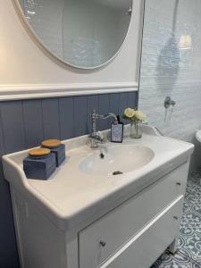 a bathroom with a white sink and a mirror at Hamptons House on Hunter with fire pit in Aberdare