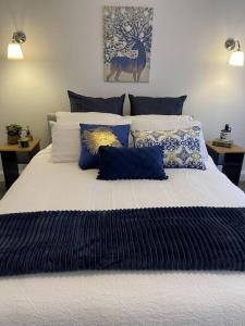 a large bed with blue and white pillows on it at Hamptons House on Hunter with fire pit in Aberdare