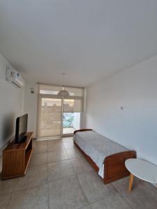 Un dormitorio con una cama, un televisor y una mesa. en Altos del Pampa, en Santa Rosa