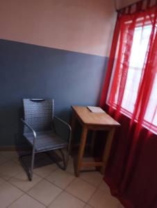 einen Stuhl und einen Tisch in einem Zimmer mit Fenster in der Unterkunft BM Akwaba in Palimé